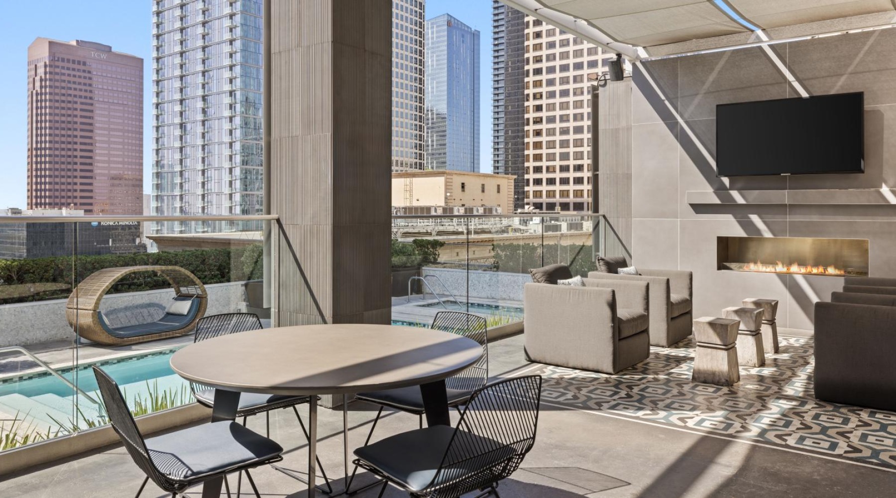 Relax and unwind poolside a patio with a table and chairs and a pool with tall buildings in the background